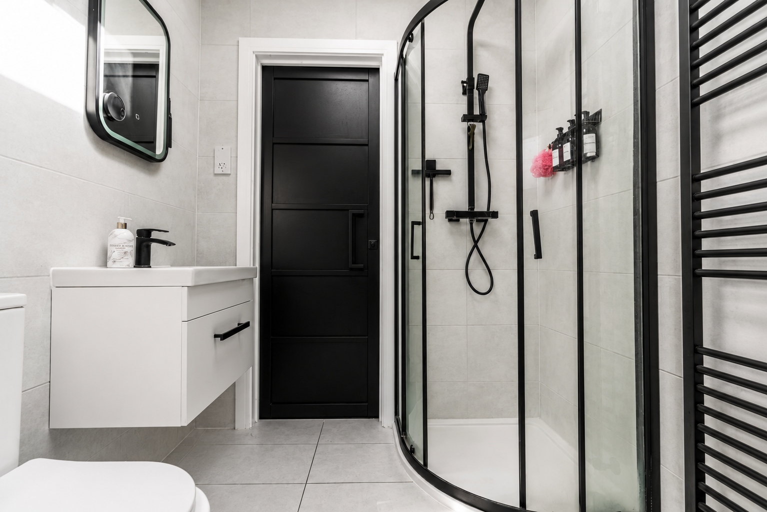 Modern tiled shower room with black fittings, kept guest ready by Oak